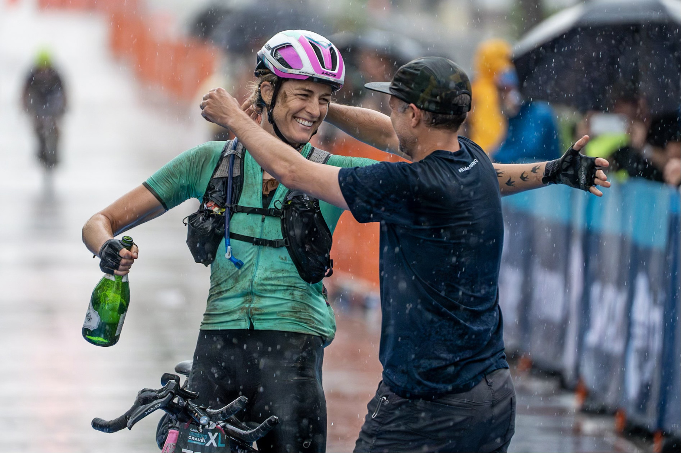 Kristen Legan and Nick Legan hugging after Kristen wins Unbound XL gravel race in the rain