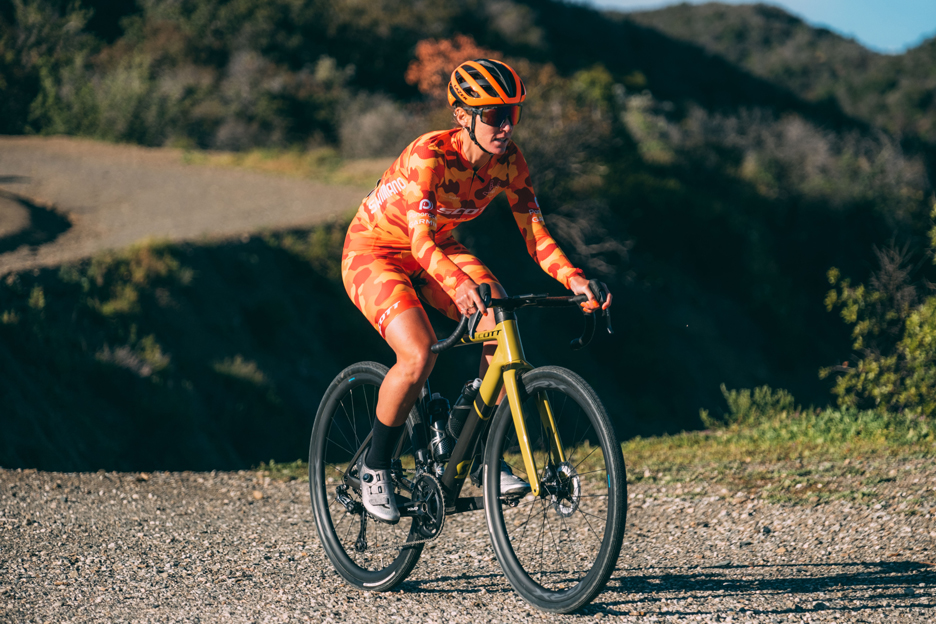 Shimano gravel athlete Iz King in her bright orange kit riding her Scott gravel bike 