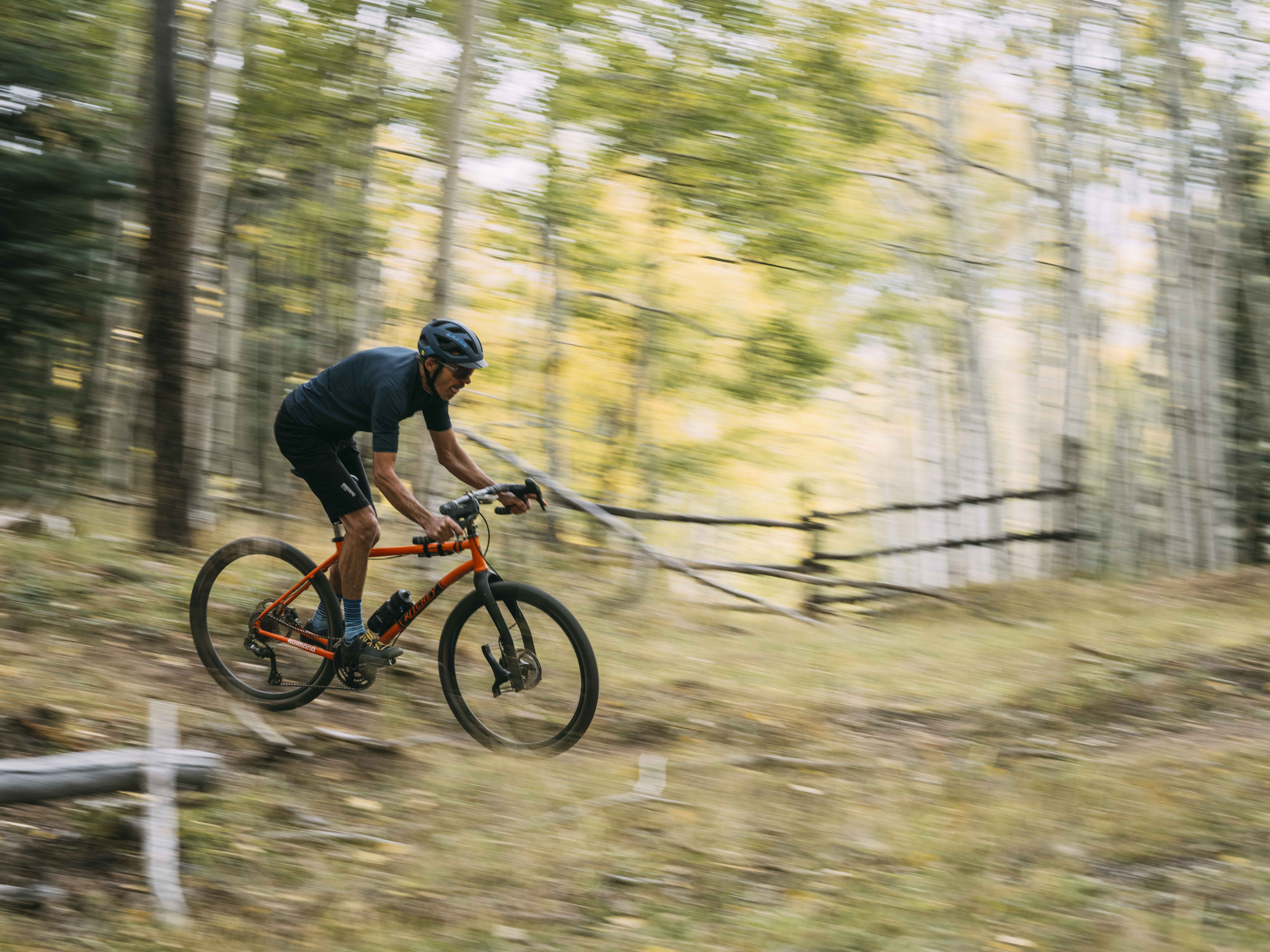 Alex Morgan cykler på sin gravelcykel gennem en skov 