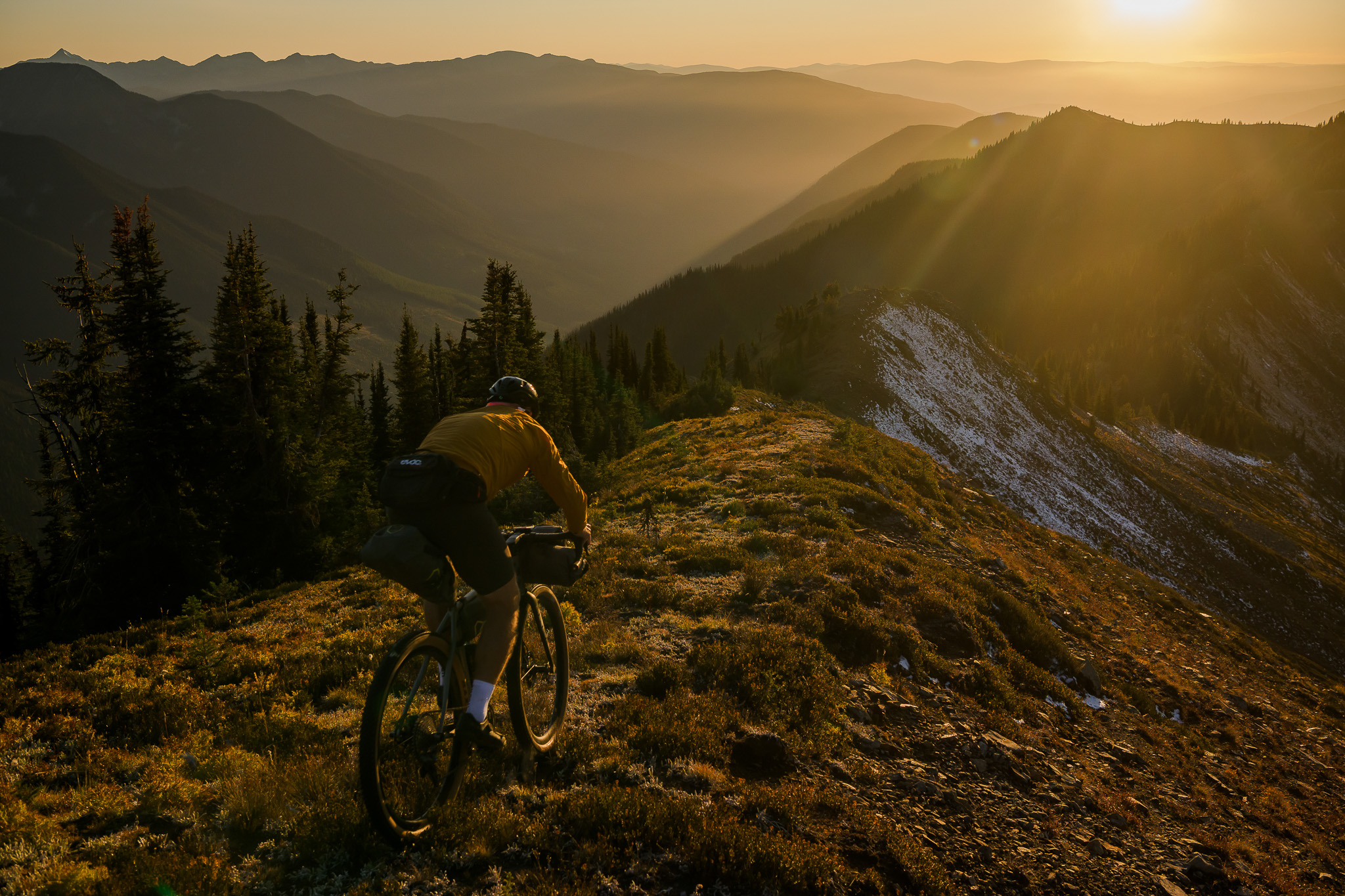 Svein Tuft riding his grave bike down a mountain at sunset 