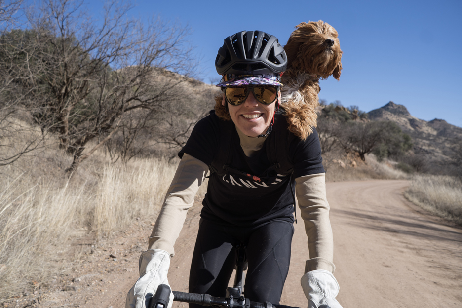 Heather Jackson riding her bike with her dog on her shoulder 